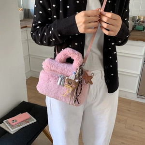 Dettaglio ravvicinato di una borsa in peluche rosa con ciondoli in metallo