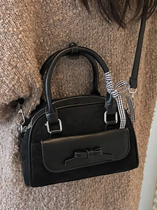 Sac Boston noir chic avec empiècements en daim et ruban décoratif sur un pull en maille