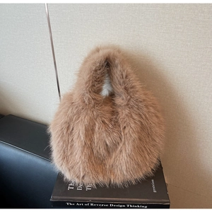 Gros plan détaillé du sac à main marron en fausse fourrure pelucheuse sur livres