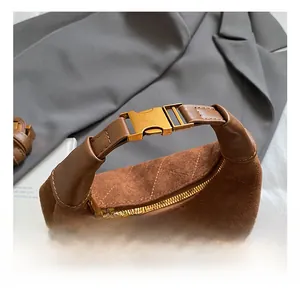 Detailed close-up of brown suede bag featuring diamond quilting and gold metal buckle