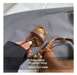 Detail of adjustable shoulder strap and decorative wooden beads on a brown suede bag