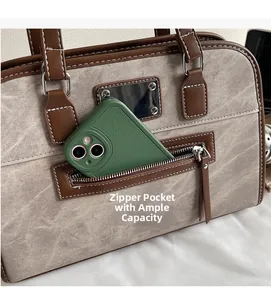 Detail of the practical front zipper pocket showing phone storage on a textured handbag