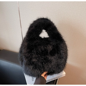 Vue détaillée de la texture douce en fausse fourrure noire sur un grand sac à main dumpling