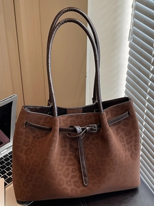 Deep brown suede leopard embossed tote bag with slim leather handles in office setting