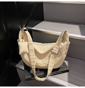 Detail of off-white crescent canvas bag with embossed letters and detachable coin pouch