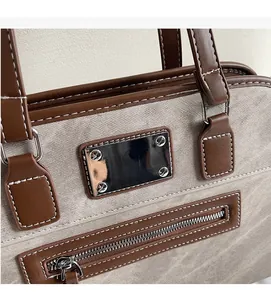 Close-up of gray twill fabric and brown leather stitching on a stylish handbag