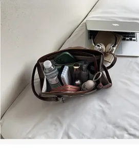 Macro view of spacious dark brown leather bag interior with multiple items for daily storage