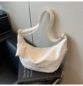Detailed close-up of a white canvas crossbody bag with adjustable strap and coin pouch