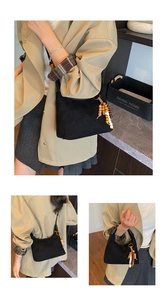 Detail of black quilted suede shoulder bag featuring retro wooden bead zipper charm