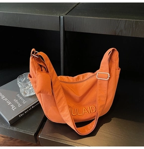 Burnt orange canvas crescent bag with NULAID embroidery and side accessory pouch