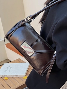 Vintage dark brown glossy baguette bag with silver buckle worn as a shoulder bag
