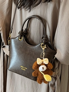 Dunkelbraune Lederhandtasche mit verstellbarem Gurt und süßem Plüschbär-Anhänger