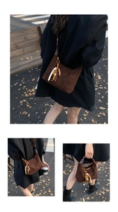 Detail of dark brown suede half-moon bag featuring triple wooden bead fringe pendants