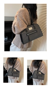Detail of grey-black shoulder bag with contrast white stitching and metal logo plate