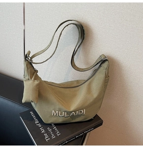 Detail of olive green crescent crossbody bag with mini pouch on black books