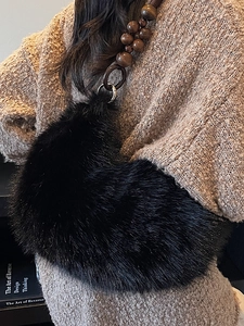 Sac croissant en peluche noire avec bandoulière en perles de bois porté par un mannequin