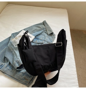 Close-up of black canvas hobo bag with adjustable strap and small square coin purse