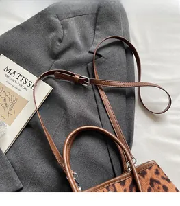 Detail of leopard print bucket bag with adjustable brown leather strap on grey blazer