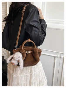 Détail du sac seau en peluche marron avec bandoulière en cuir et pendentif lapin blanc