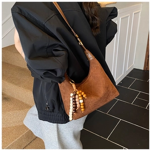 Detail of brown suede hobo bag with diamond quilting and colorful beaded tassel pendant