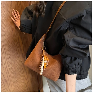Close-up of brown suede shoulder bag with quilted pattern and colorful wooden bead tassel