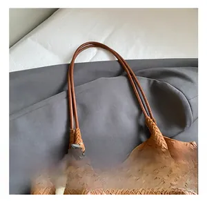 Close-up of brown woven leather tote with thin handle and wooden bead charm detail