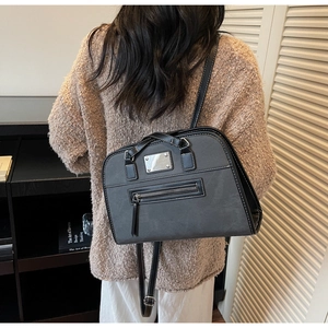 Detail view of grey and black crossbody bag showing front zipper and metal plate detail