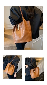 Detail view of woven brown leather tote bag with elegant beaded charm and shoulder strap