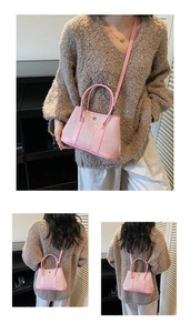 Detail of pink suede bucket bag with round metal buckle and adjustable shoulder strap