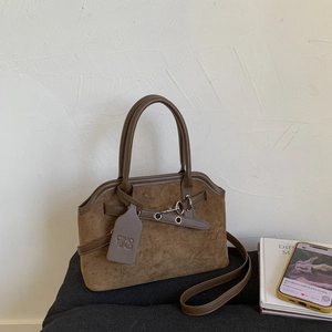 Detailed view of dark brown suede tote bag with decorative straps and metal eyelet accents
