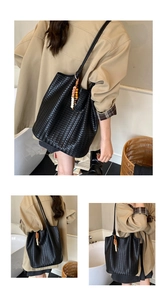 Close-up of black woven leather tote bag with elegant beaded pendant detail