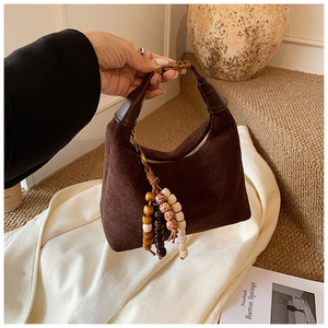 Detail of dark brown suede hobo bag featuring ethnic wooden bead tassel and gold hardware