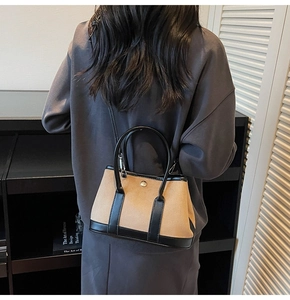 Detail of a minimalist contrast bucket bag worn by a model in a modern room setting