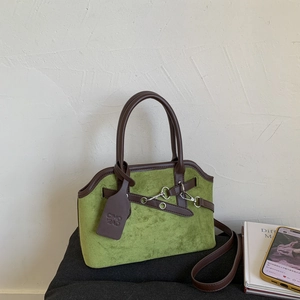 Close-up of green suede tote bag showing detailed stitching and silver hardware lock