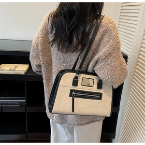 Detail shot of the large beige suede and black leather patchwork bag worn by model