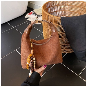 Detail of brown quilted suede hobo bag featuring ethnic beads and gold hardware