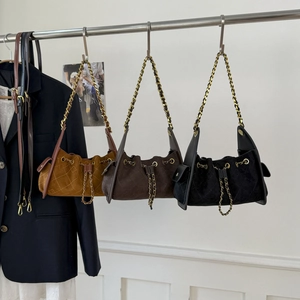 Close-up of quilted suede bucket bags with drawstring closure and metal chain straps