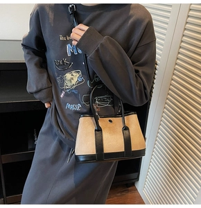 Side view of model carrying a bicolor contrast bucket bag in tan and black leather