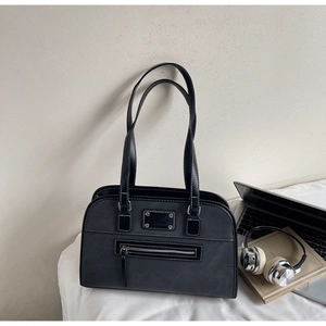 Detail of dark grey leather tote with white stitching and front zipper on a desk