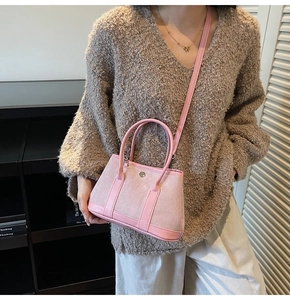 Pink patchwork bucket bag with round handles and metal buckle shown on a model