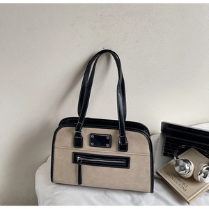 Close-up of beige suede tote bag with black leather trim and contrast stitching detail