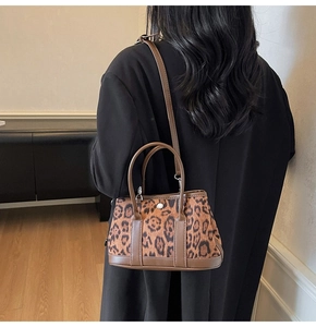 Detail view of leopard print plush bucket bag with brown leather handles and strap