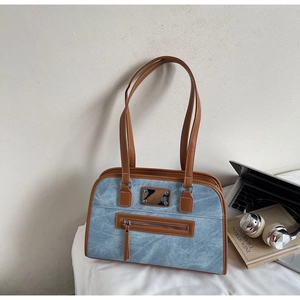 Close-up of retro denim and leather patchwork shoulder bag in a lifestyle office setting