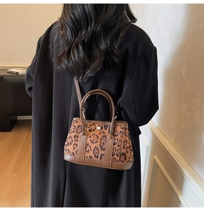 Detail of leopard print bucket bag featuring brown leather trim and metal hardware