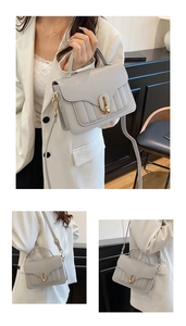 Close-up of grey pebbled leather handbag with vertical stitching and gold metal buckle