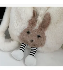 Close-up of white plush bucket bag with brown rabbit face and striped legs detail