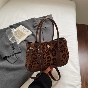 Detailed macro view of leopard print bucket bag with brown handles and silver hardware