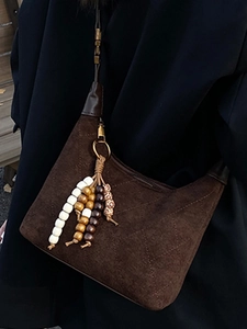 Dark brown quilted half-moon shoulder bag with suede texture and wooden bead charm