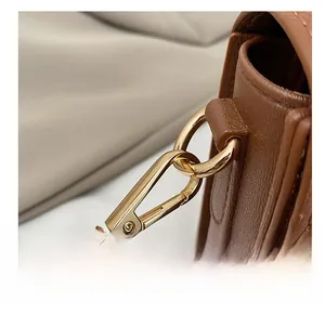 Macro shot of caramel brown litchi grain leather bag with premium gold metal hook hardware