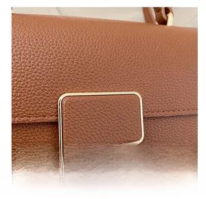 Detail of brown lychee grain leather handbag featuring a polished gold rectangular buckle